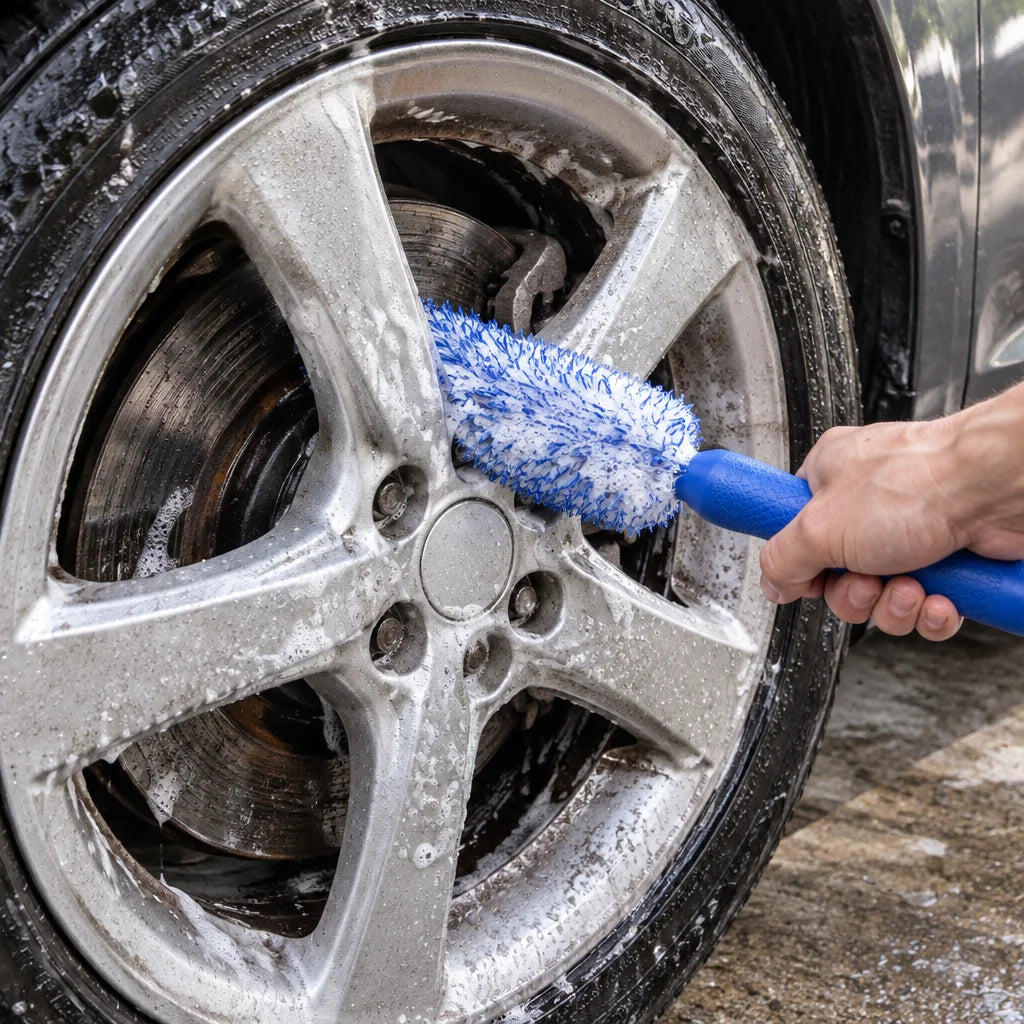 Show this exact wheel and rim detailing brush reaching between the spokes of a real car wheel during