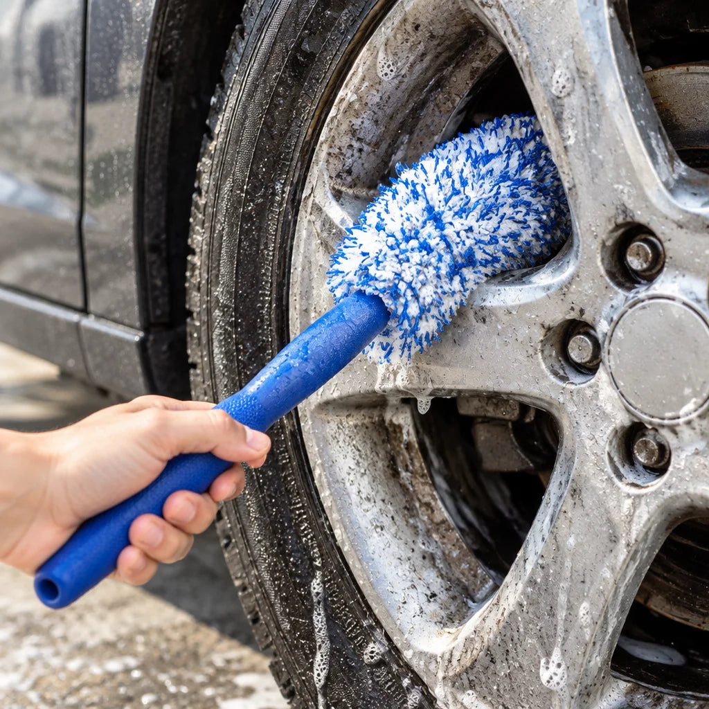 Show this exact wheel and rim detailing brush reaching between the spokes of a real car wheel during