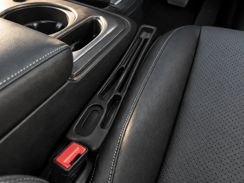 Show a close detail of this exact organizer positioned in the seat gap beside the center console, em
