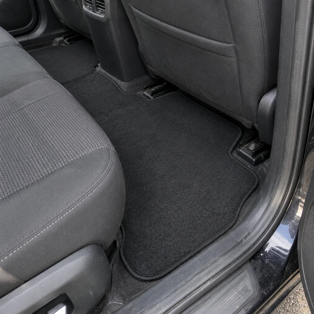 Show these exact universal carpet car floor mats in the rear footwell of a real vehicle, with realis